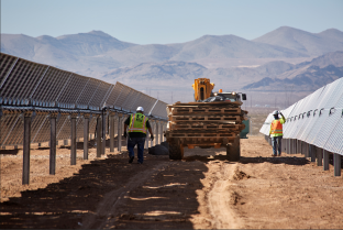 View of people working on the Arrow Canyon solar project in between a row of panels. 