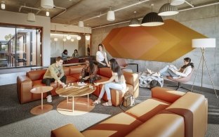 Group of people gathering in a common area at couches and tables.