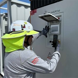 A person looking at an electrical component of a renewable energy project