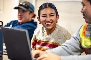 A person smiling at another person with a laptop in the foreground