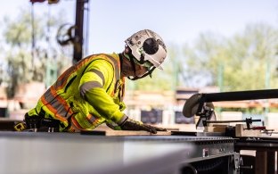 A person wearing PPE using a saw on a jobsite
