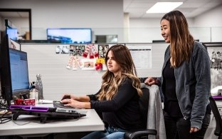 Two people working at a computer in an office