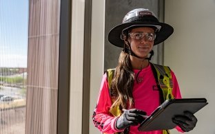 A person wearing PPE and holding a tablet. 