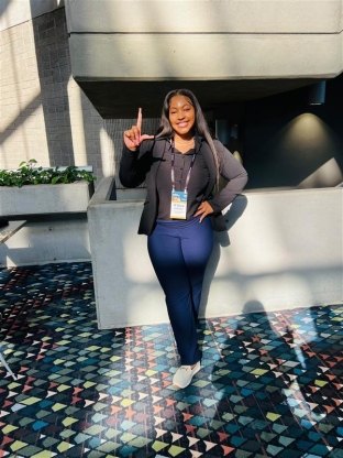 A person holding up a hand signal while dressed for a conference