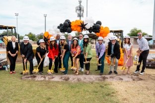 A group of people with shovels and hardhats at the groundbreaking