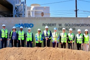 A group of people standing with vests, hardhats, and shovels at a groundbreaking event.