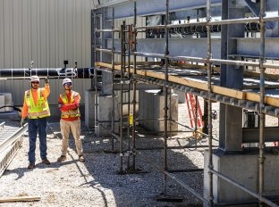 Two construction works standing next to scaffolding on a construction site