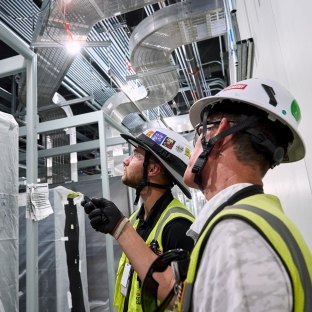 Two people looking at equipment and wearing PPE