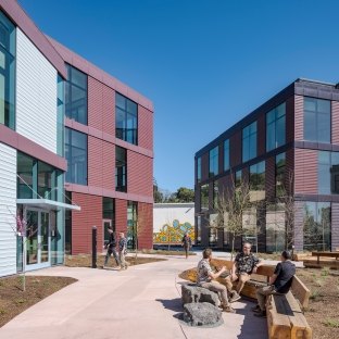Exterior walkway with a bench and people seated and talking