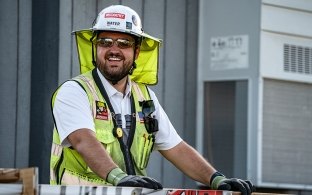 A person wearing PPE on a jobsite and smiling