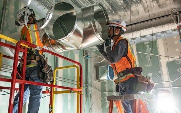 Two people installing HVAC equipment.