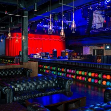 A bowling area with couches and shelves of neon-colored bowling balls.