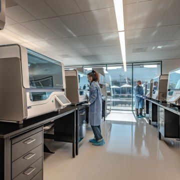 A lab area with a person wearing a mask and working in the lab. 