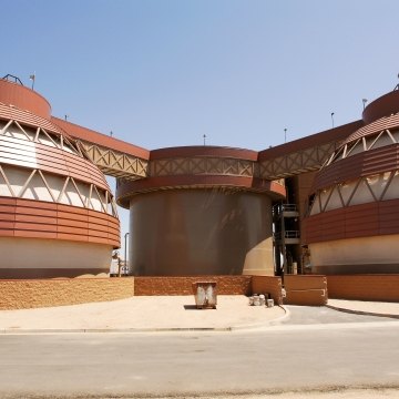 The beige and brown holding tanks at a large water facility.