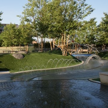 A fountain, bench, and greenery area at the park