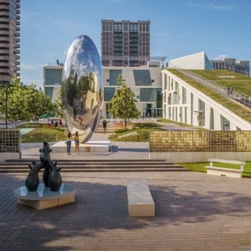 Outdoor image of the fine art park with people walking on concrete surrounded by grass