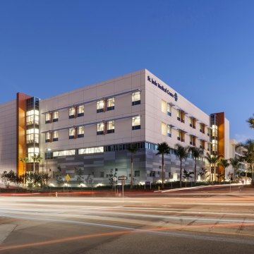 Outdoor image of the entire medical center with parking and palm trees