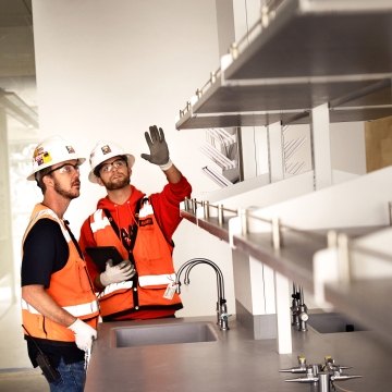 Two construction workers talking in a lab.