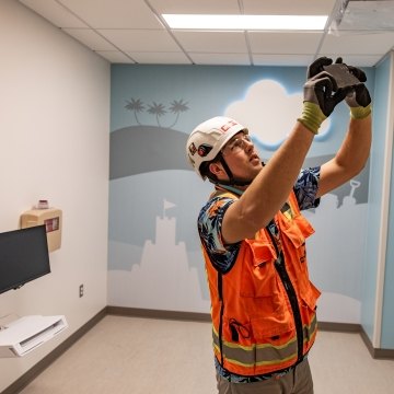 A person wearing PPE taking a photo in a hospital room