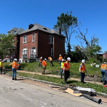 Group of people cleaning up an area in St. Louis following a tornado.