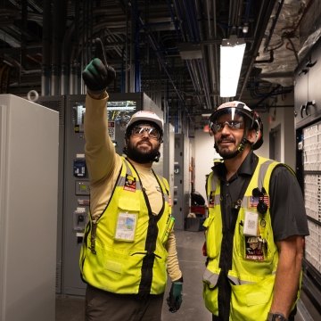 Two people wearing PPE and pointing
