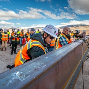 Construction workers prepare steel beam.