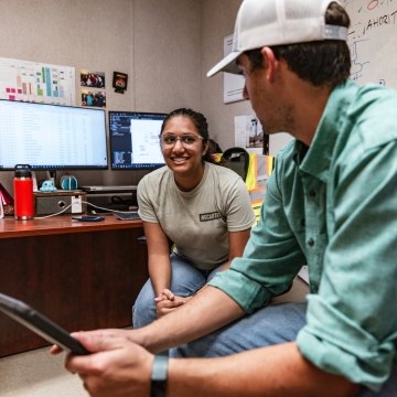 Two people sitting and talking at a desk