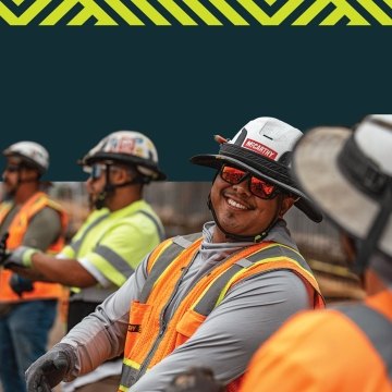 A person wearing PPE and smiling at another person.