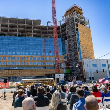 A group of people sitting at a ceremony outside of the hospital under construction
