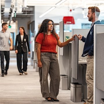 People standing and talking near a desk