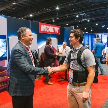 Two people shaking hands with the McCarthy booth in the background